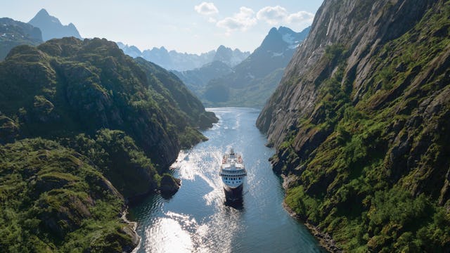 Bilden visar ett av Havila Kystrutens fartyg som glider genom Trollfjorden.