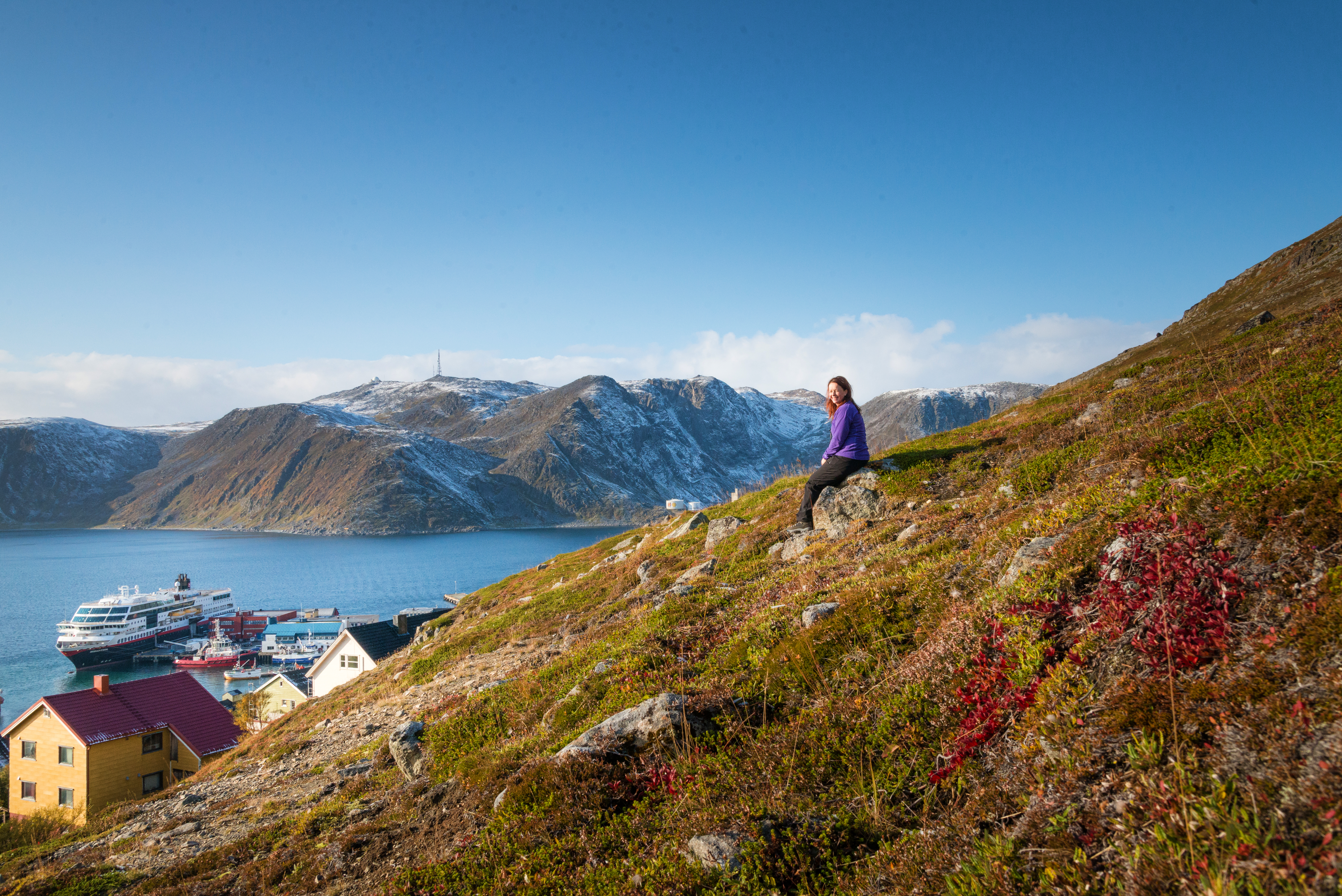 Bilden visar en person som sitter och njuter av utsikten över berg och dalar.