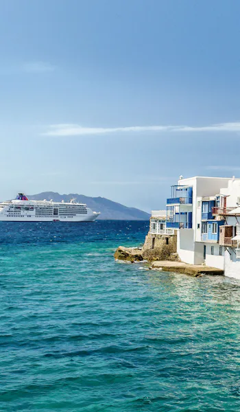 Bilden visar Hapag-LLoyds fartyg i Medelhavet utanför Mykonos kust. På bilden syns turkost hav och vitkalkade hus med blå balkonger och fönsterluckor.
