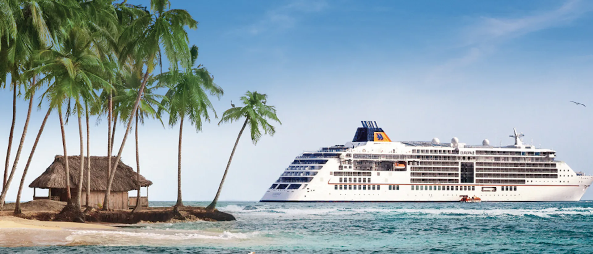 Bilden visar Hapag-Lloyds fartyg MS Europa 2 vid en karibisk strand med palmer.