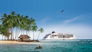 Bilden visar Hapag-Lloyds fartyg MS Europa 2 vid en karibisk strand med palmer.