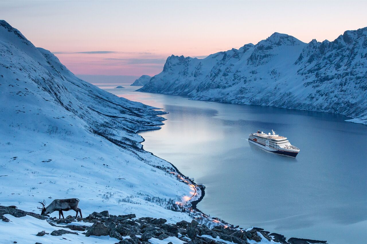 Bilden visar fartyget Hanseatic Nature som kryssar i ett vinterlandskap i Skandinavien