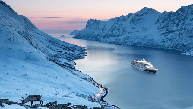 Bilden visar fartyget Hanseatic Nature som kryssar i ett vinterlandskap i Skandinavien